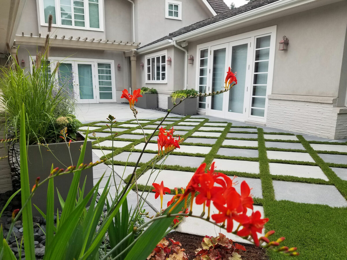 Bonney Lake Landscapes laid grass pavers in a manicured backyard with bright red crocosmia diablitos in bloom near Seattle, Washington.