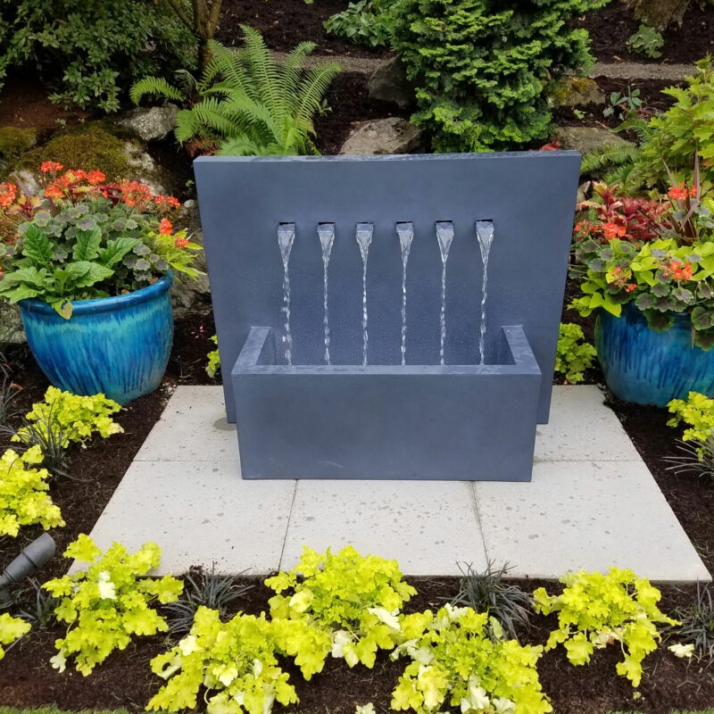 Unique and completely custom rock water fountain with outdoor lighting, paver patio and lush landscape design by Bonney Lake Landscapes in Seattle, Washington.